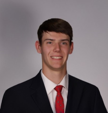 Erik Gerdts in a black suit jacket and red tie against a grey background