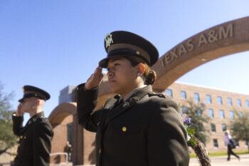 A photo of two cadets saluting during a ceremony outside the arches on the Texas A&M University campus.