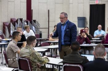 A photo of a man in a classroom talking to a student.