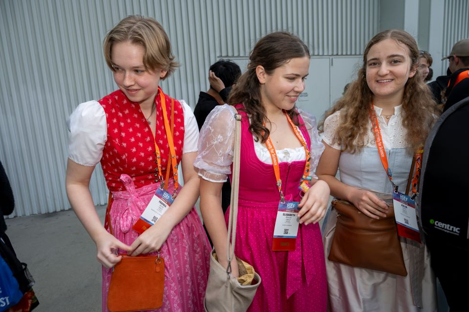 Three members of Team Germany in dirndls hand out pins.