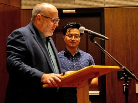 A faculty member stands at a podium.