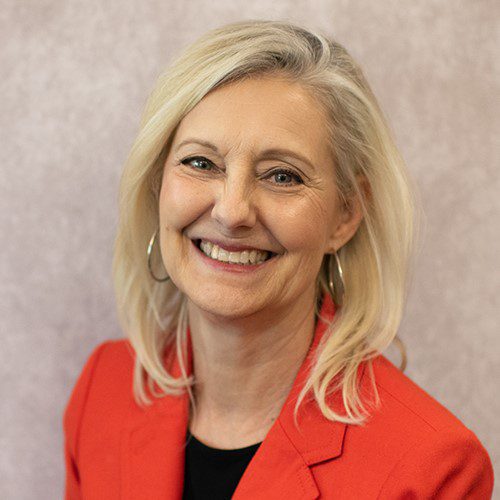 A smiling woman wearing an orange suit