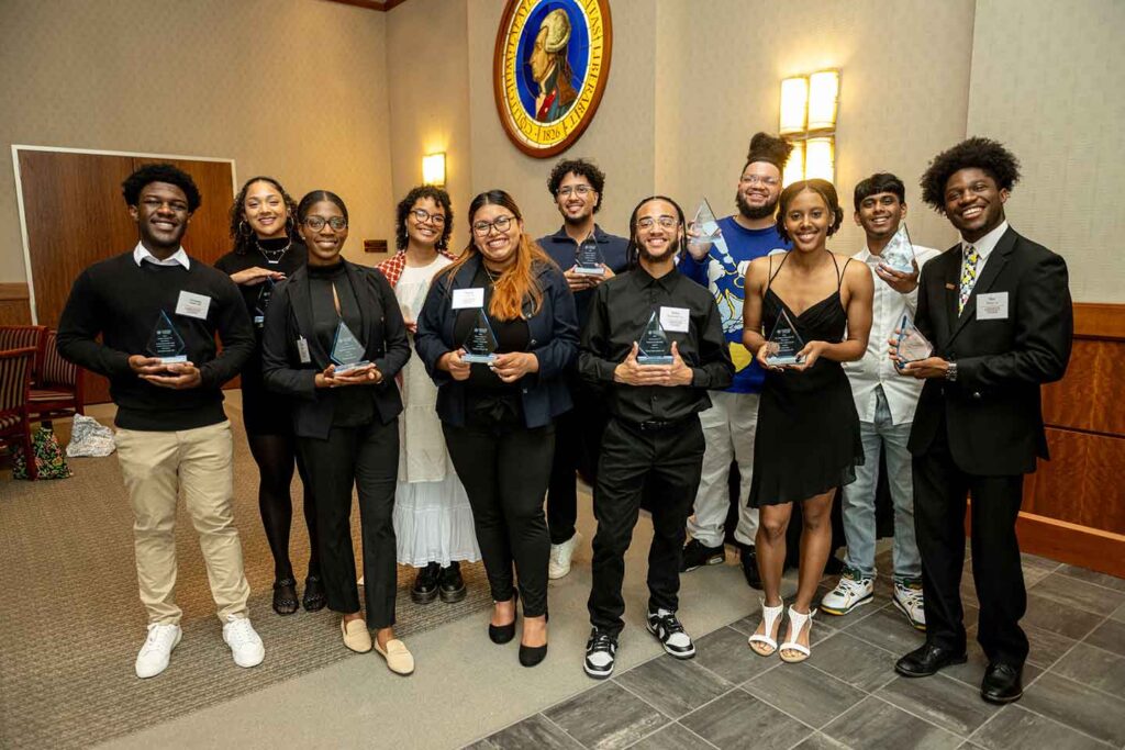 A group of student stand together holding their awards.