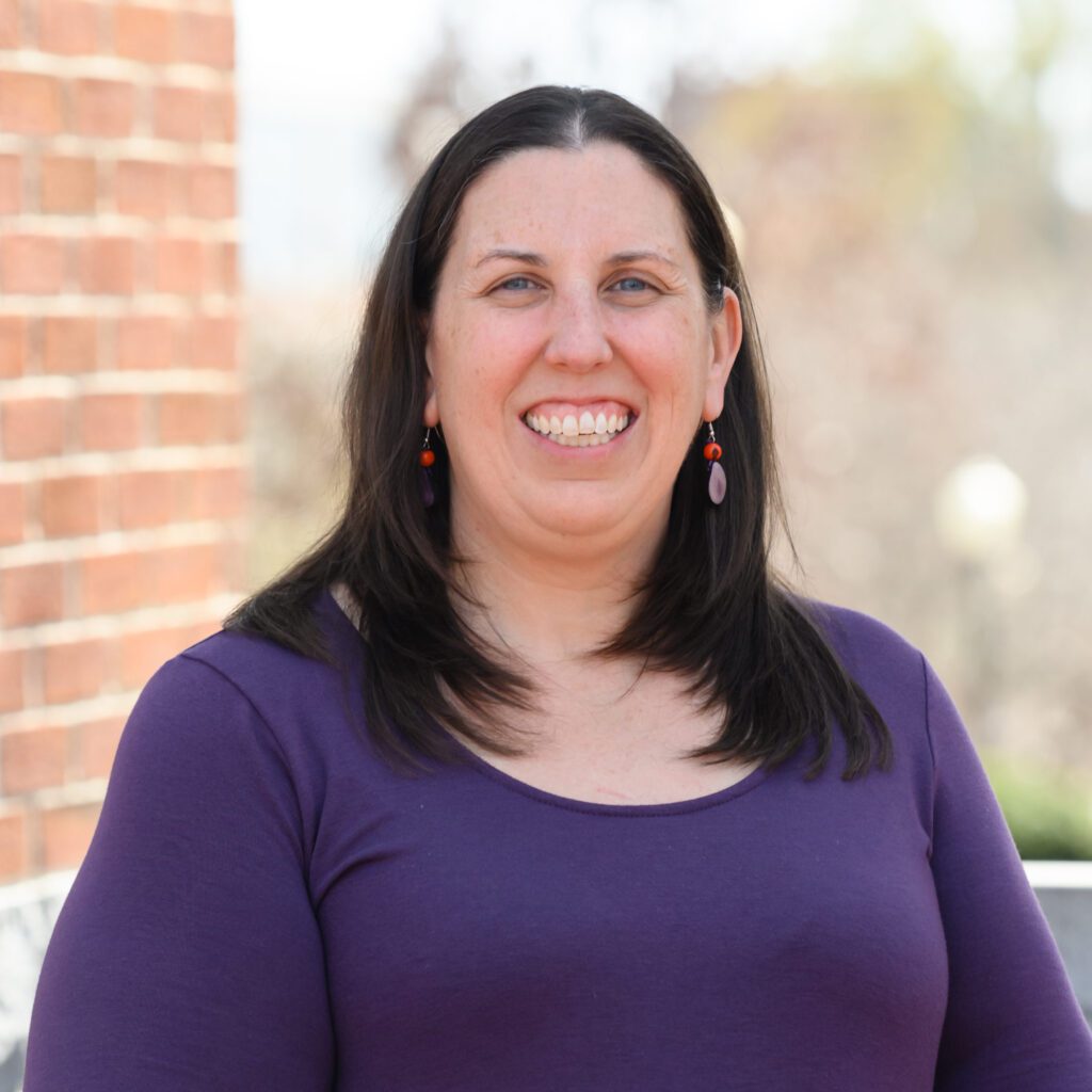 A smiling woman wearing a purple shirt
