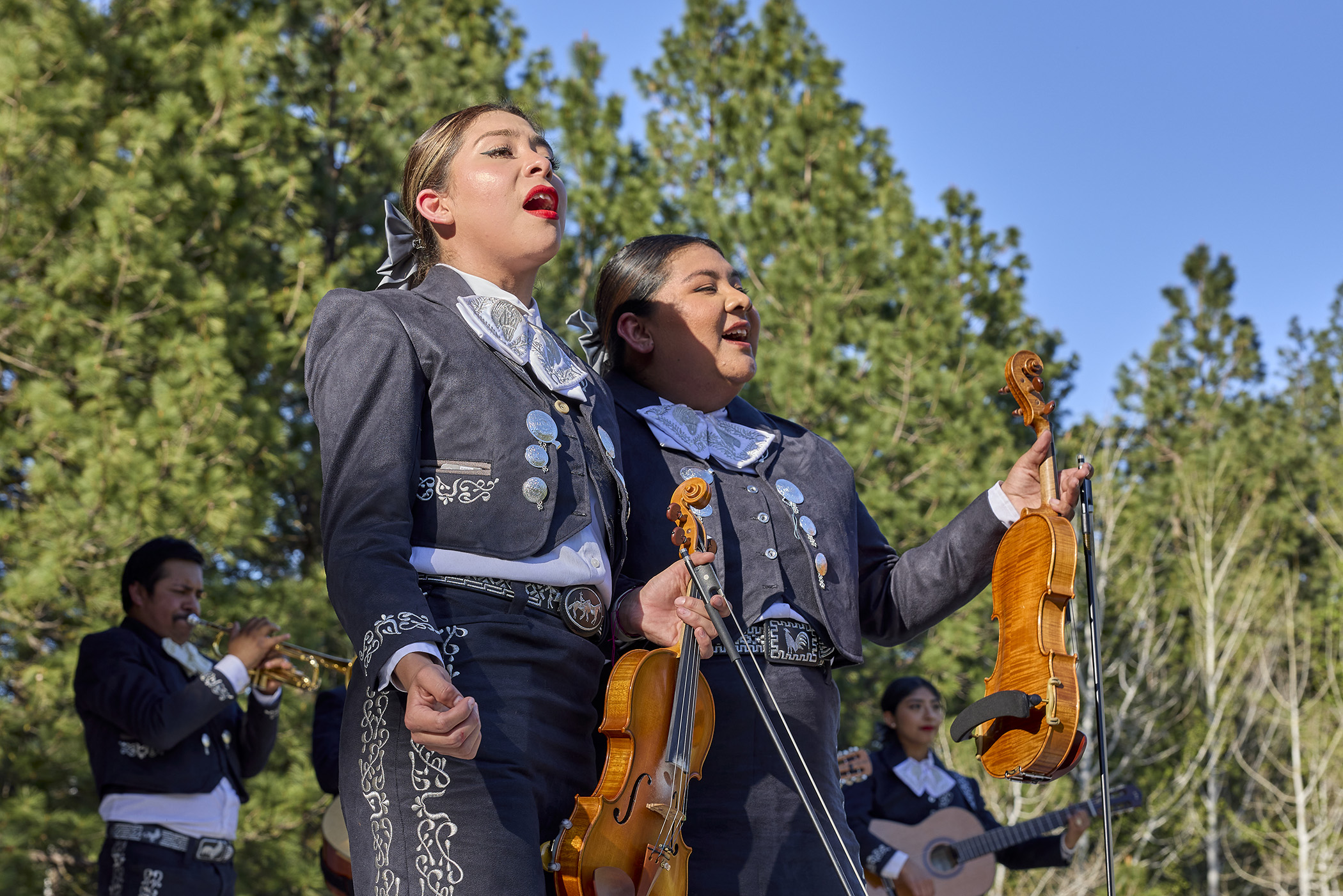 Two women in Mariachi outfits performing outdoors