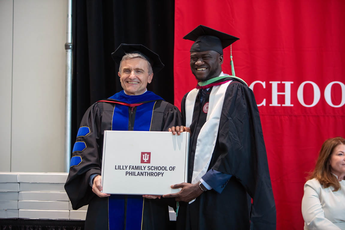 Dean Amir Pasic poses for photo with graduating student at commencement.