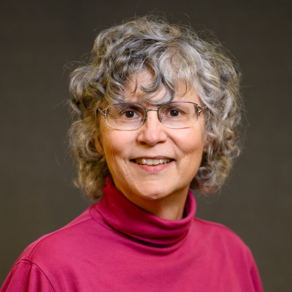 A woman wearing glasses and a pink turtleneck sweater