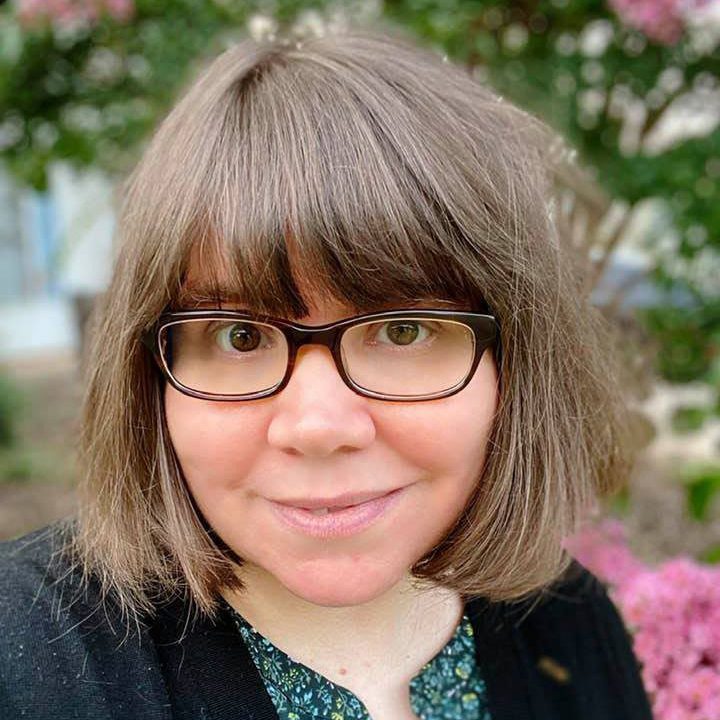 A smiling woman with brown glasses