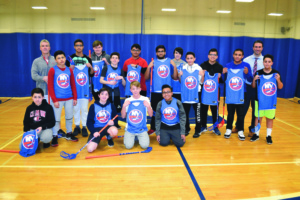 Division Avenue High School physical education teacher Thomas Tuttle (left), Principal John Coscia (right) and students with the donated floorball equipment from the New York Islanders hockey team. Photo courtesy of the Levittown Public Schools