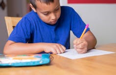 A boy at a desk writing.