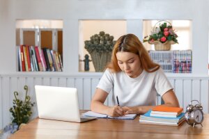 Asian female student sitting taking notes in the library.