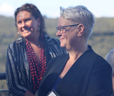 Penny Sharpe looking towards the left hand screen, with woman in the background. 