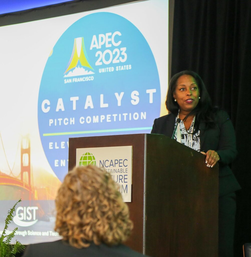 Acting Assistant Secretary Littlejohn delivers remarks at the APEC Catalyst Pitch Competition, San Francisco, September 2023. She is speaking from behind a lectern and there is an APEC2023 Catalyst banner behind her.