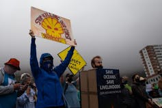 Protestors holding placards that say