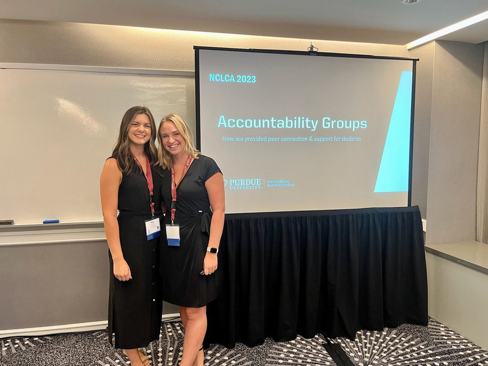 pictured: joanna cardarelli and teammate mary kirk stand by a projector during a presentation