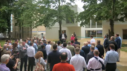 BBC A crowd gathers as a ribbon is prepared to be cut outside Minster Exchange in Cheltenham