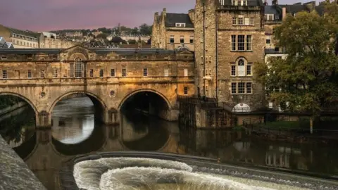 Getty Images The river flowing down cascading steps in Bath with Georgian buildings in the background and a bridge with three tunnels underneath it.