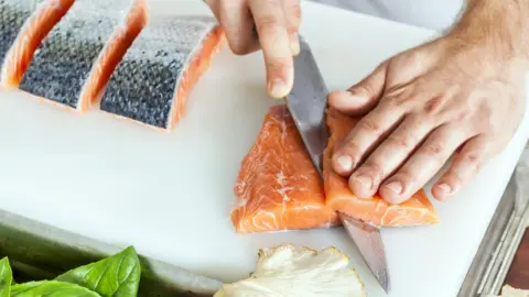 Getty Images Cutting raw salmon