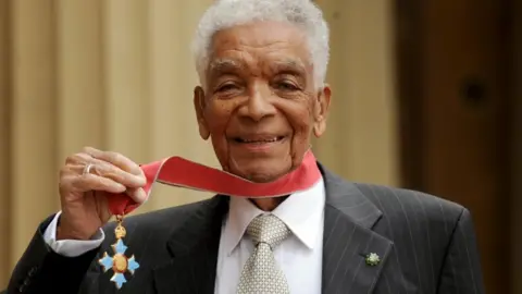 PA Media Earl Cameron outside Buckingham Palace with his CBE