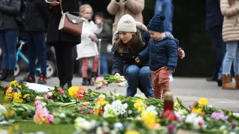 EPA A woman and child leave flowers outside Windsor Castle