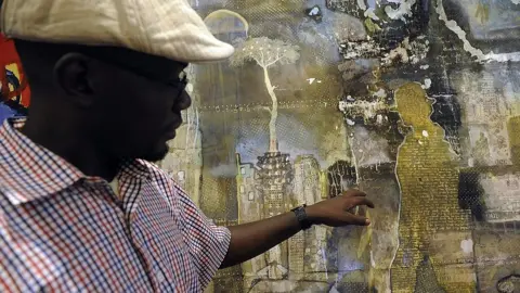 AFP Kenyan painter Paul Oditi looks at his work displayed for the first commercial auction of east African art on November 4, 2013 in Nairobi, on the eve of the the auction.