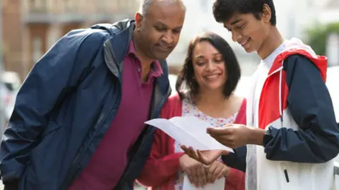 Getty Images Milind Patel opens his GCSE results with his parents at Ffynone House School on August 12, 2021 in Swansea