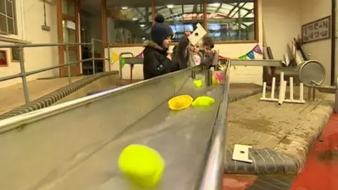 BBC Children sending objects down a metal water chute