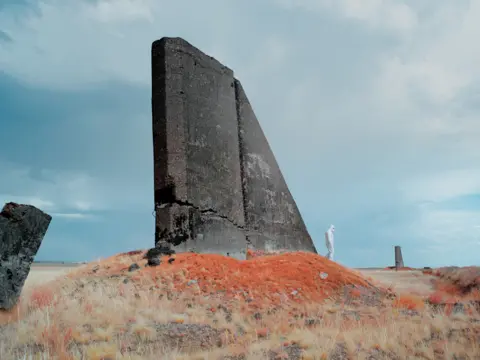 EDDO HARTMANN Scientist in protective clothing walks through landscape of a remote area of Kazakhstan used for nuclear testing
