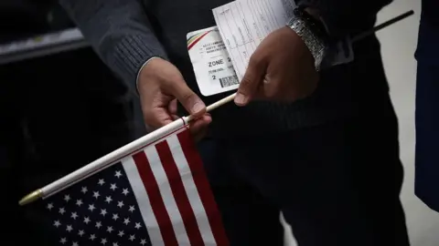 Getty Images A man holds travel documents after arriving from Yemen at Dulles International airport in Washington, DC.