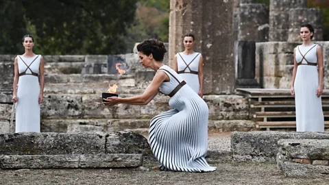 Getty Images In Olympia, Greece, several months before each Olympics, an actress in ancient Hellenic clothing lights the flame from the sun’s rays via a parabolic mirror (Credit: Getty Images)