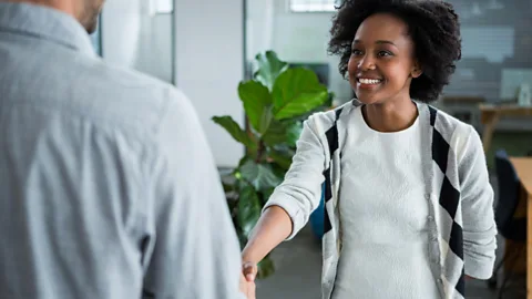 Alamy Young woman shaking hands with a colleague