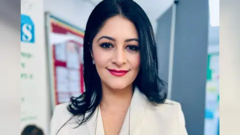 Shabina Asad Qayyum Shabina Asad Qayyum wearing a white suit, smiling for the camera.