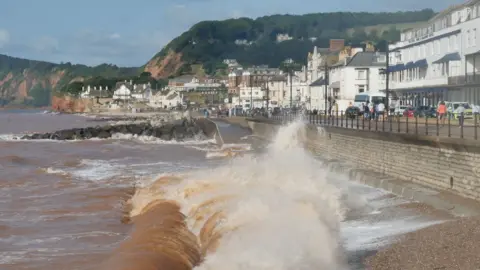 Waves breaking and splashing onto the esplanade in the coastal town of Sidmouth