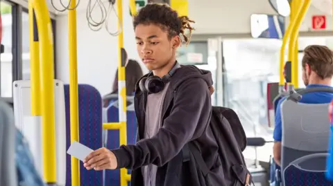 Getty Images Young man wearing black hoodie, grey t-shirt and headphones uses his bus pass
