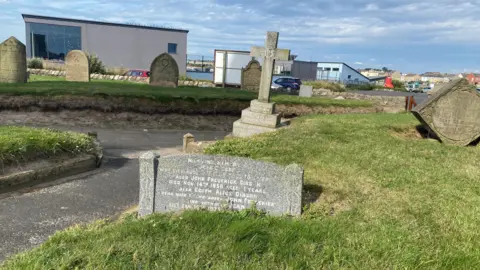 A gravestone stuck into the ground and hardly visible