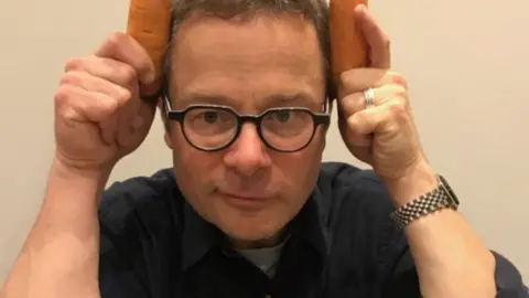 KEO films Hugh Fearnley-Whittingstall holding carrots to his head.