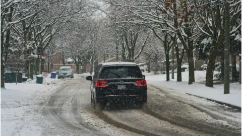NurPhoto A car driving on a snowy street in Toronto