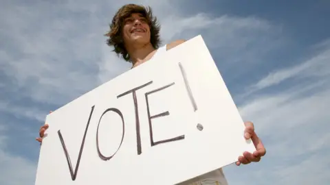 Getty Images Young person holding a voting card