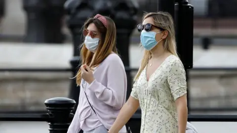 Getty Images Two women walking wearing face masks