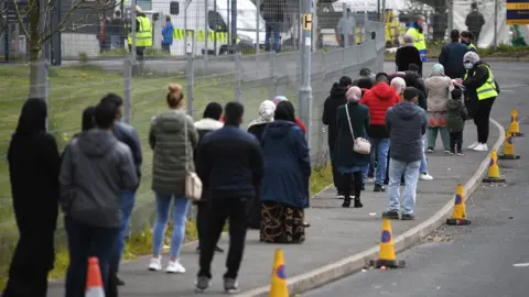 Getty Images People queuing outside a vaccination centre