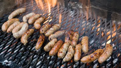 Getty Images Sausages on a BBQ