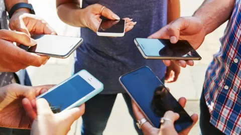 Getty Images Friends on their smartphones