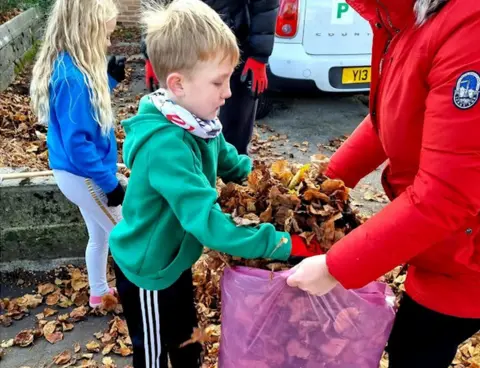 YGC Rebal Mams child filling bag with leaves