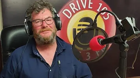 Mark Burns Mark Burns presenting a radio show on Drive 105