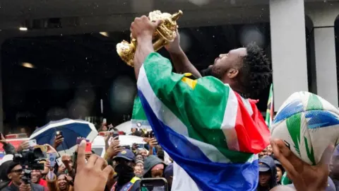 AFP South Africa's flanker and captain Siya Kolisi holds the Webb Ellis Cup as he meets with supporters after the South African rugby team's arrival at the OR Tambo International airport in Ekurhuleni on October 31, 2023