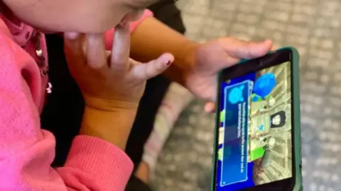 Lumi Nova A child holding an iPhone with the Lumi App on the screen