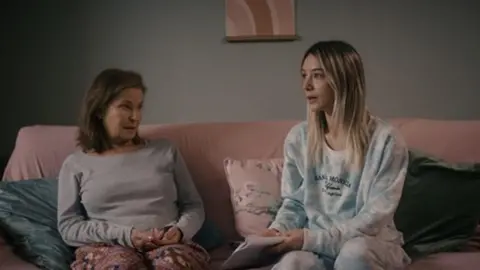 W4Films Stephanie Beacham as Peg sitting on a sofa next to Eloise Smith, who plays her grand daughter Chloe