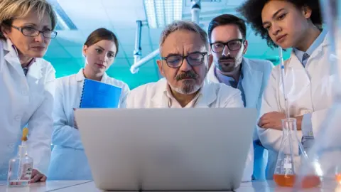Getty Images Team of scientists look at a laptop