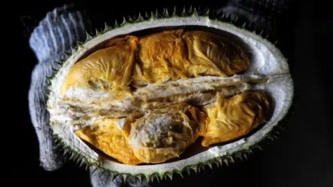 Getty Images A vendor displays the cross section of a durian at a roadside fruit shop