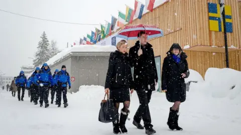 Getty Images People walk through the resort town of Davos as snow falls ahead of the World Economic Forum (WEF) 2018 annual meeting, on January 22, 2018 in Davos